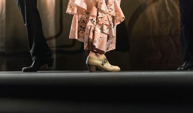 Two dancers standing back to back in the spotlight