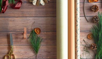 Neutral wrapping paper with Christmas tree branches and gold scissors