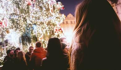 Person looking up at decorated outdoor Christmas tree