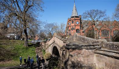 A walking tour group standing by The Dell and bridge in Port Sunlight