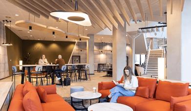 A person sitting relaxing on a large red sofa in the reception area.