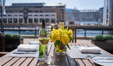 A table set up for dinner with a vase of flowers and a glass of wine.
