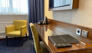 A hotel room with a chair and a desk.