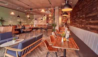 A dining area with sofas, tables and chairs.