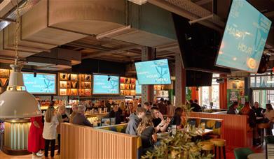 People in the Black Cat Club bar talking/drinking and enjoying themselves.