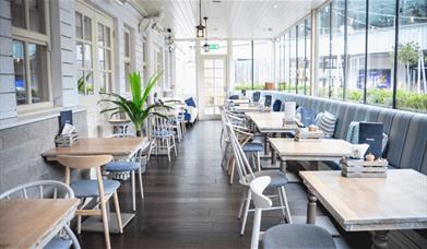 Inside of the club house in a room that looks like a conservatory with tables and chairs set out.