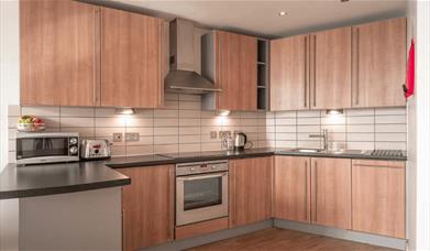 A kitchen area in Premier Suites equipped with a microwave, oven and a kettle.