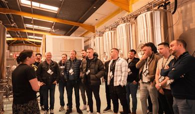 Liverpool Tour Experiences at a brewery with a person standing in front of a tour giving a tour to a group.
