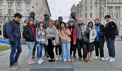 Architecture walking tours of Liverpool with a group of people standing in front of The Beatles statues.