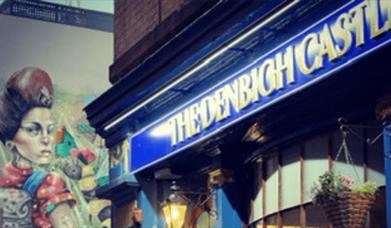 The exterior of the pub is a traditional, victorian facade painted blue with gold detail.