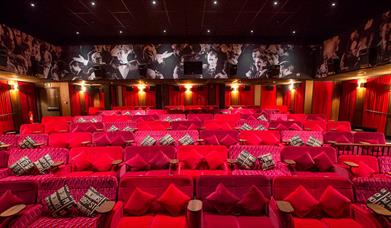 Plush red couches in a dimly lit cinema